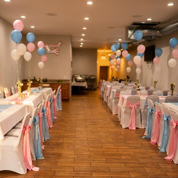 Restaurant dining room set up for an event with tables, chairs, and pink and blue balloons.